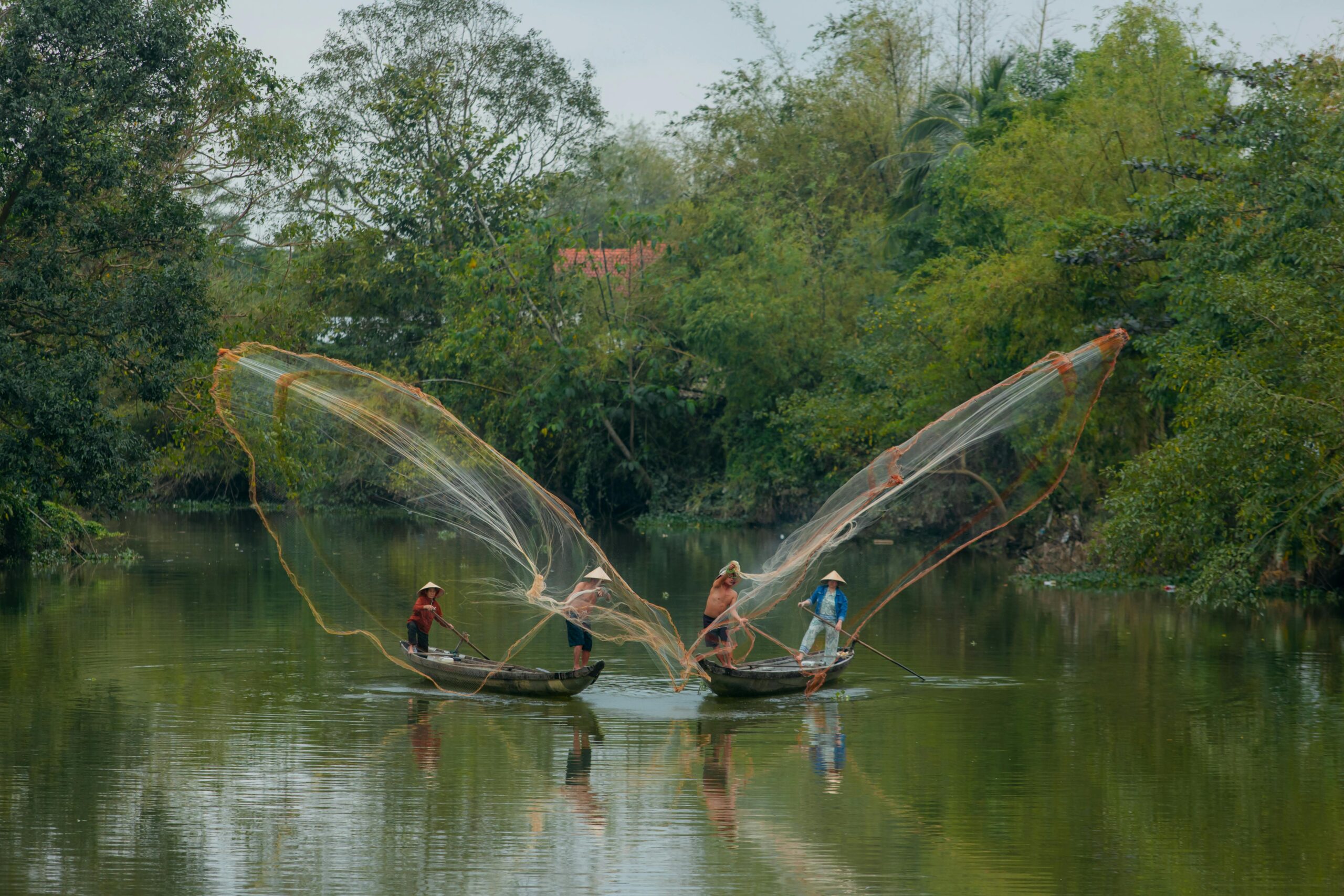 Fishermen casting nets on a peaceful river in Huế, capturing traditional Vietnamese fishing practices.